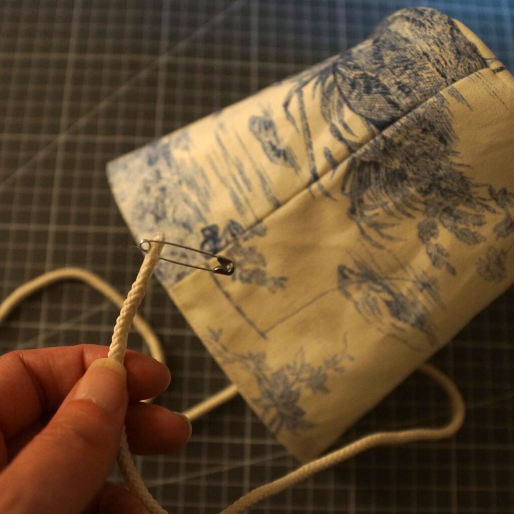 Faire passer le cordon dans la coulisse du pochon